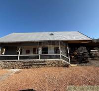 A family house in Ratkovské Bystré with a metal roof and a stone base in the garden.