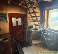 The interior of a family house with a metal staircase and a wooden table, light walls.