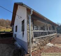 The exterior of a family house in Ratkovské Bystré with sunny weather and a stone base.