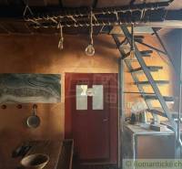 Interior of a family house with wooden stairs, a rustic table, and an artistic painting on the wall.
