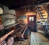 Rustic kitchen in a family house with wooden decor, ladder staircase, and brick motif.