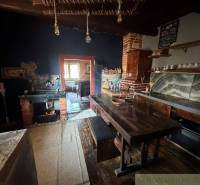 A kitchen in a family house with an antique interior, a wooden table, and a brick stove.