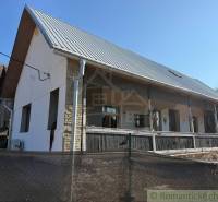 A family house in Ratkovské Bystré with a garden, white facade, and metal roof.