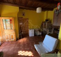 A room in a family house with a brick floor, wooden ceiling, and yellow walls.