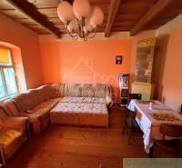 Living room with a corner sofa, wooden decor flooring, and a tiled stove in a family house.
