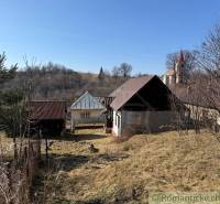 A family house in Lipovec with a church tower in the background surrounded by hilly countryside.
