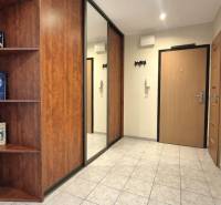 Entrance hallway in a 2-room apartment with tiles and shelves with books.
