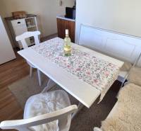 Dining area with white furniture, a refrigerator, and a wooden decor floor in a 2-room apartment.