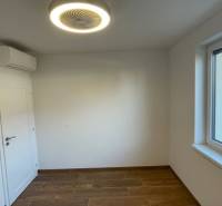 A room in a family house with a wooden decor floor, air conditioning, and a window.