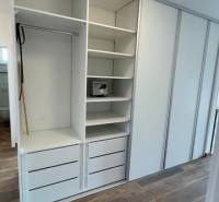 White built-in wardrobe with shelves and drawers in a family house, floor with wooden decor.