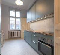 A kitchen with white tiles in a 3-room apartment, equipped with a modern kitchen unit and a stove.