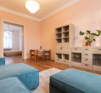 Living room in a three-room apartment with a wooden decor floor and pastel walls.
