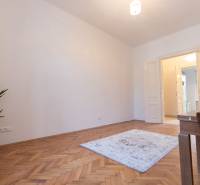 A room in a 3-room apartment with a wooden decor floor, a plant, a carpet.