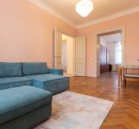 A room in a 3-room apartment with a blue sofa, wooden floor decor, and a dining area.