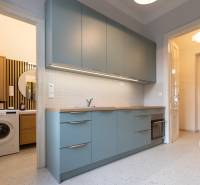 A kitchen with blue cabinets, a sink, and a washing machine in a 3-room apartment inspired by retro style.