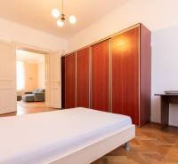 A bedroom with wood-patterned flooring, white furniture, and a spacious wardrobe.