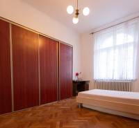 Bedroom with a bed, wooden decor flooring, large wardrobe in a 3-room apartment.