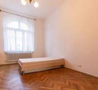 A bright room with a bed and a wooden decor floor in a 3-room apartment.