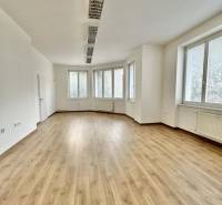 Offices with large windows and wooden decor flooring.