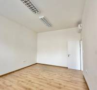 Offices with wood-patterned flooring and white walls, ceiling lights.