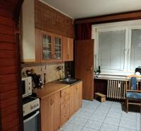 A kitchen in a 2-room apartment with a kitchen unit and tiles, a window with blinds.