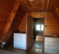 Interior of a cabin with wooden walls, a dresser, and a floor with a wooden decor.
