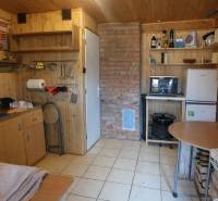A kitchen in a cabin with wooden decor and a brick chimney, equipped with basic furniture.