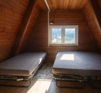 Attic room in a cottage with two beds and a wooden decor floor.
