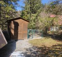 A wooden shelter and fence in a natural setting near a cottage in Oščadnica.