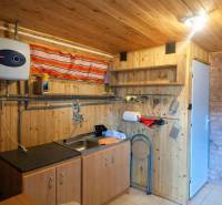Interior of a cabin with wooden decor, kitchen unit, and brick cladding.