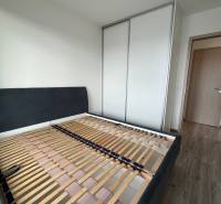 A bedroom in a 3-room apartment with a bed frame and a built-in wardrobe.