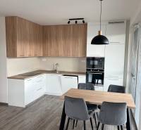 A kitchen in a 3-room apartment with a corner kitchen unit and a wooden decor floor.