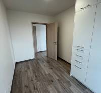 A room in a 3-room apartment with a wood-patterned floor and built-in storage space.