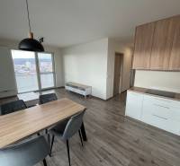 Dining area with wood-patterned flooring in a 3-room apartment, kitchen unit, and view.