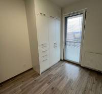 A room with a white wardrobe, a wooden-patterned floor, and balcony doors in a 3-room apartment.