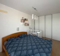 Bedroom in a 3-room apartment with a double bed, a baby crib, and a floor with a wooden decor.