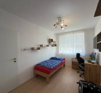 Children's room in a three-room apartment with a wooden decor floor, a desk, a bed.