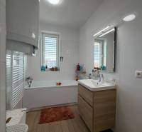 Bathroom with a bathtub and a sink in a 3-room apartment, white tiles, floor with wood decor.