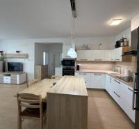 A kitchen in a 3-room apartment, a floor with a wooden decor, modern appliances, and a dining table.