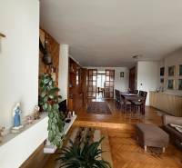Living room in a family house with a wooden decor floor, a dining table, and a cross on the wall.