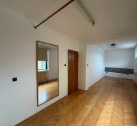 A room in a family house with a wooden decor floor, a mirror, and a window.