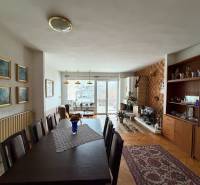 Living room in a family house with a wood-patterned floor, dining table, and fireplace.