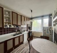 A kitchen in a family house with wooden cabinets, a round table, and a floor with a wooden decor.