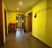 A hallway with coat racks and yellow walls, a floor with a wooden decor in a family house.
