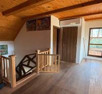 A hallway in a family house with a wooden decor floor and wooden railing.