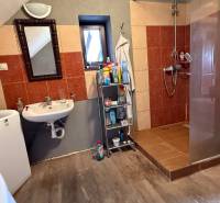 A bathroom in a family house with a washing machine, a mirror, and a shower enclosure.