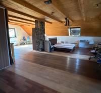 Attic room with a bed, wardrobe, and wooden decor flooring in a family house.