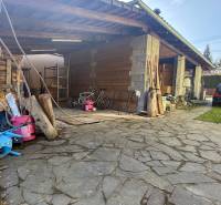 A family house in Lutila with a wooden shelter, a stone courtyard, and a parked car.