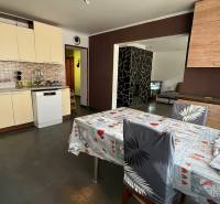 A kitchen in a family house with ceramic tiles, a dining table, and a dishwasher.