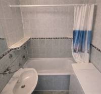 Bathroom with a bathtub and a sink in a 2-room apartment, tiled walls.